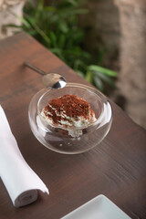 Tiramisu dessert in glass bowl with spoon on wooden table showcasing culinary artistry and indulgence concept