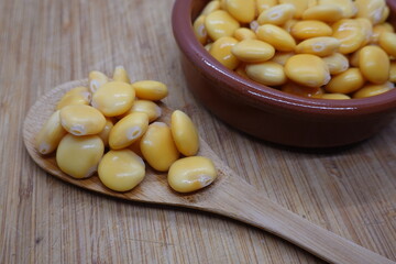 Lupine beans resting on wooden spoon and terracotta bowl