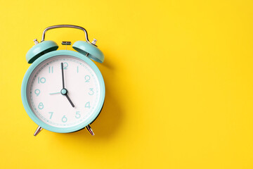 Turquoise alarm clock on yellow background, top view. Space for text