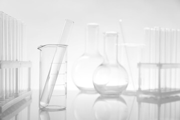 Laboratory glassware on mirror surface against light background