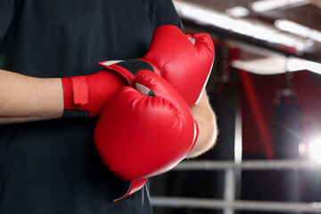 Man putting on protective boxing gloves in training center, closeup