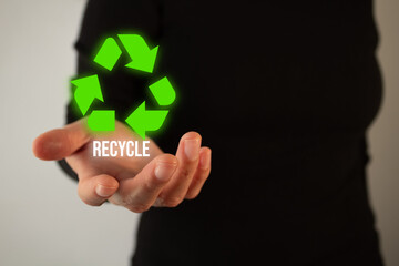 
A person is holding a hand with a green circle and the word recycle written on it. Concept of recycling and the importance of taking care of the environment
