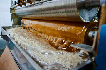 Innovative glue-spreading machine in action featuring a bath for bottom hot glue application,...