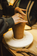 Hands skillfully shape a clay pot in a pottery studio. The workshop encourages creativity and focuses on teaching pottery techniques to beginners in a relaxed atmosphere.