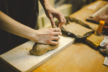 Hands skillfully shape a clay pot in a pottery studio. The workshop encourages creativity and focuses on teaching pottery techniques to beginners in a relaxed atmosphere.