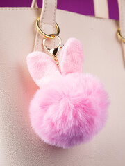 Close up of cute fluffy pink bunny bag keychain on white  bag