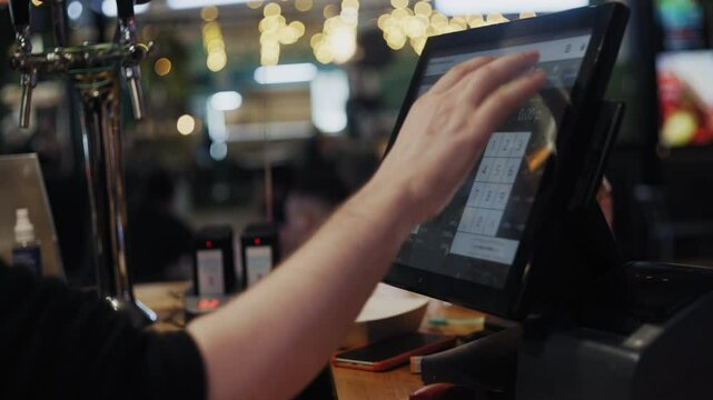 Close-up of hands operating a digital point-of-sale terminal in a fast food restaurant.