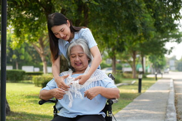 Two women, the daughter pushing a stroller with her elderly mother, walk in the garden and chat happily.