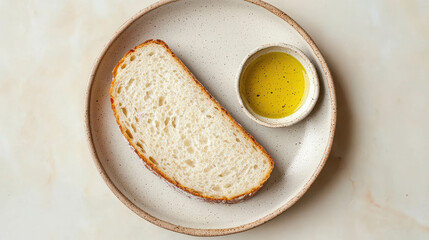 Naklejka premium Freshly Baked Bread Slice with Olive Oil Dish on a Simple Plate