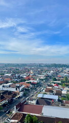 Aerial view of Solo city with traditional red-roofed houses, modern buildings, and clear morning skies blending into the distant horizon.