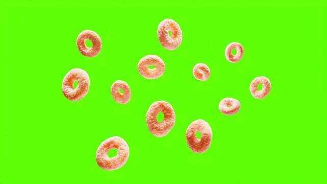 Aros de cereal de ma&iacute;z y trigo girando lentamente, sobre un fondo verde croma. 