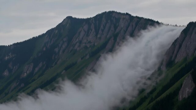 Clouds rolling over mountain peak in timelapse scenery