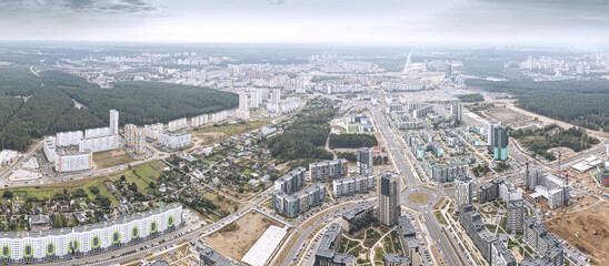 panoramic aerial view of urban residential district with multistorey apartment buildings and highways with roundabout intersection.