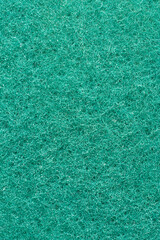 close-up macro view of textured bright green rough fibrous surface of cleaning sponge, small dense...