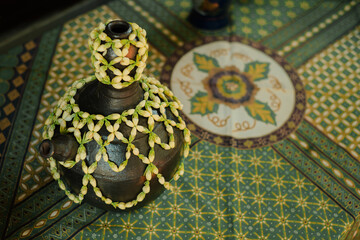 A traditional clay pot with green petals decoration. The pot is used for Javanese traditional wedding ceremony called Siraman.