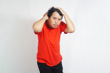 Indonesian people pose tidying their hair wearing red t-shirts on a plain white background                        