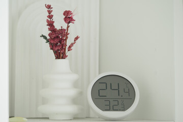 Decorative vase with dried flowers next to a temperature clock