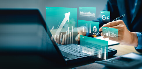 Modern financial analysis and business intelligence concept with digital dashboard interface, data visualization, and futuristic charts. Businessman using laptop and pen for strategic planning.