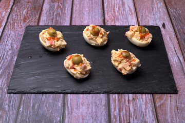 Stuffed eggs with olives on slate stone