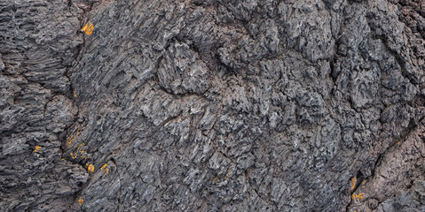 Nahaufnahme einer grau-schwarzen Lava-Textur auf dem Boden. Porös, rissig und steinern, ideal als Stock-Textur oder Foto-Hintergrund. Eindruck von geschmolzenem Gestein.