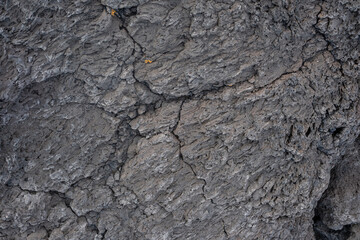Nahaufnahme einer grau-schwarzen Lava-Textur auf dem Boden. Porös, rissig und steinern, ideal als Stock-Textur oder Foto-Hintergrund. Eindruck von geschmolzenem Gestein.