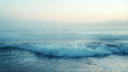 Fototapeta premium Dreamy coastal vista showcasing rolling waves under a soft hazy sky backdrop