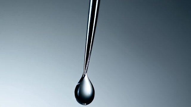Macro shot shows clear droplet slowly forming at bevelled metal tip of sterile, uncapped dental anesthetic needle against bright background, emphasizing precision