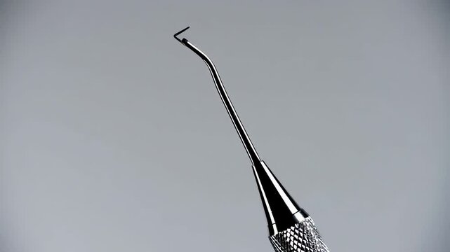 Extreme macro shot focuses on sharp, fine tip of dental explorer probe, gleaming under intense light against clean background, highlighting its delicate precision