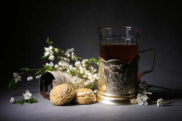 On a gray background, a glass of tea, gingerbread and branches of a fruit tree