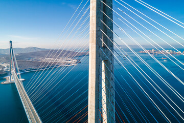 Aerial view of the cable-stayed bridge in Vladivostok, highlighting its towering pillars and cables against a backdrop of clear skies and calm waters