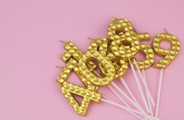 Many golden birthday candles on pink background, room for text.	