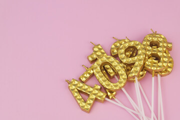 Gold birthday candles on pink background, copy space for text.