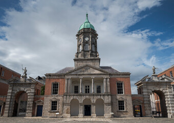 Dublin Castle with its classical architecture, prominent clock tower, and dome, set against a partly cloudy sky