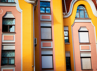 Colorful modern apartment building facade with bright yellow and pink brick walls featuring...