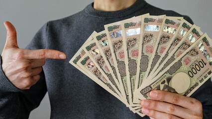 大量の一万円札を持ち指差す人物