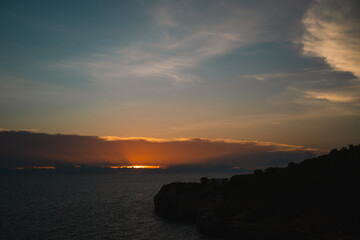 Obraz premium The island glowed beneath the summer sky as the sun set over the ocean, painting the seascape in warm hues—an unforgettable moment in a perfect travel escape.
