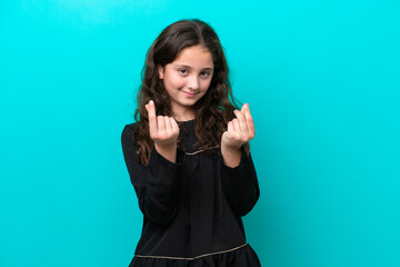 Fototapeta premium Little girl isolated on blue background making money gesture