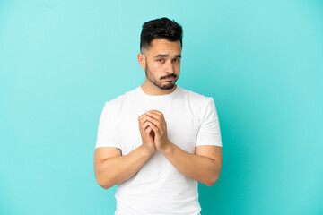 Young caucasian man isolated on blue background scheming something