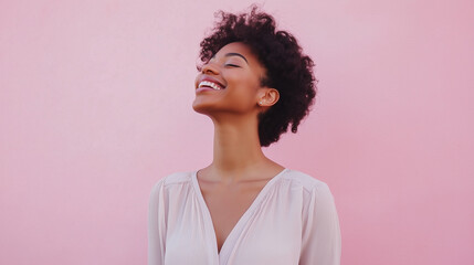 A cheerful woman in a light blouse stands in front of a pastel pink background, smiling with her eyes closed, radiating happiness, calmness, and a gentle personality smiling woman,