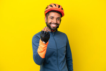 Young cyclist Brazilian man isolated on yellow background making money gesture