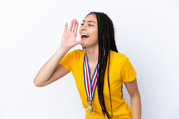 Teenager girl with braids and medals over isolated pink background shouting with mouth wide open to...