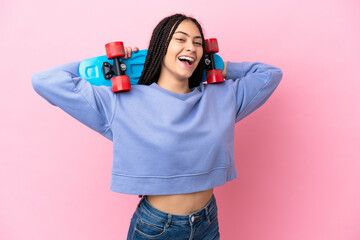 Teenager girl with braids over isolated pink background with a skate © luismolinero
