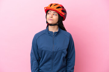 Teenager cyclist girl isolated on pink background looking to the side