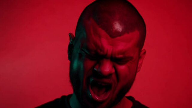 Close-up of a man with a mohawk and facial piercings, harsh neon light, static video, solid red background