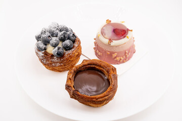 A close-up shot captures three delectable mini pastries arranged on a white plate. 