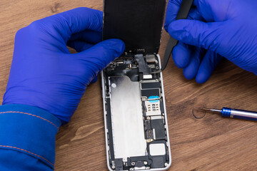 Hands of a craftsman repairing a broken phone display, close-up