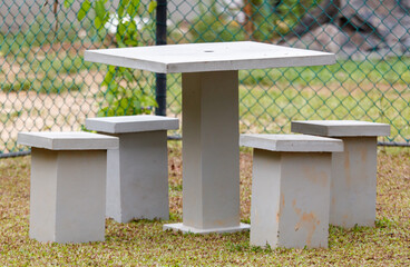 A concrete table with four chairs and a bench