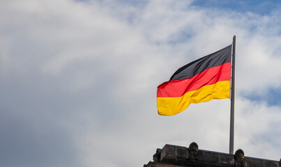 German flag waving proudly against a cloudy sky, representing national identity and pride. The...