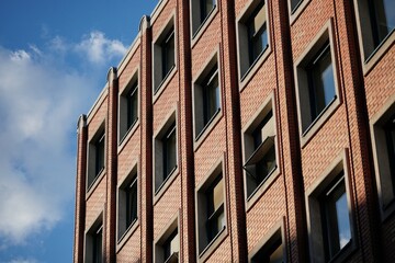 A high-angle shot captures the striking architecture of a brick building, its windows reflecting the sky