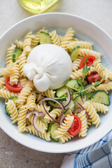 Plate of fusilli pasta with burrata cheese and vegetables, vertical shot, close-up, selective focus